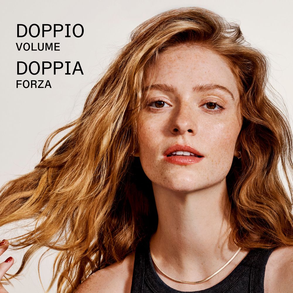 Frau mit langen, roten Haaren und Sommersprossen. Text: DOPPIO VOLUME DOPPIA FORZA.