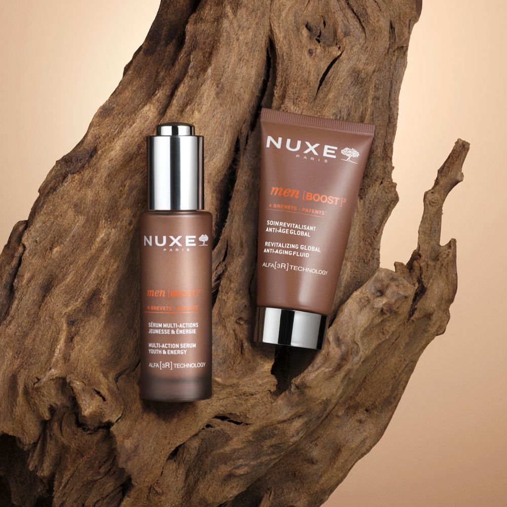 Produkt-Set: Flasche und Tube auf Holz. Aufschrift: Nuxe Paris, Men Boost, Revitalizing Global Anti-Age Fluid.