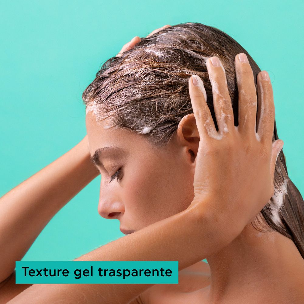 Frau wendet transparentes Gel auf ihr nasses Haar an, Schaum auf Kopfhaut und Händen.