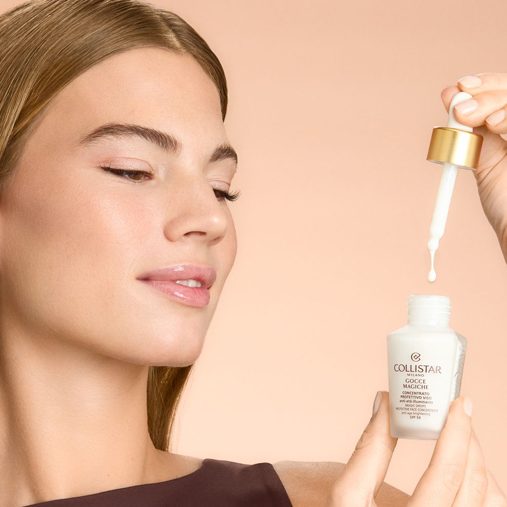 Frau hält Fläschchen und Pipette. Produkt tropft aus der Pipette. Beige Hintergrund.