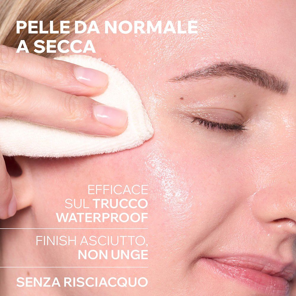 Eine Hand hält ein weiches, weißes Pad auf der Haut einer Frau, um Make-up zu entfernen.
