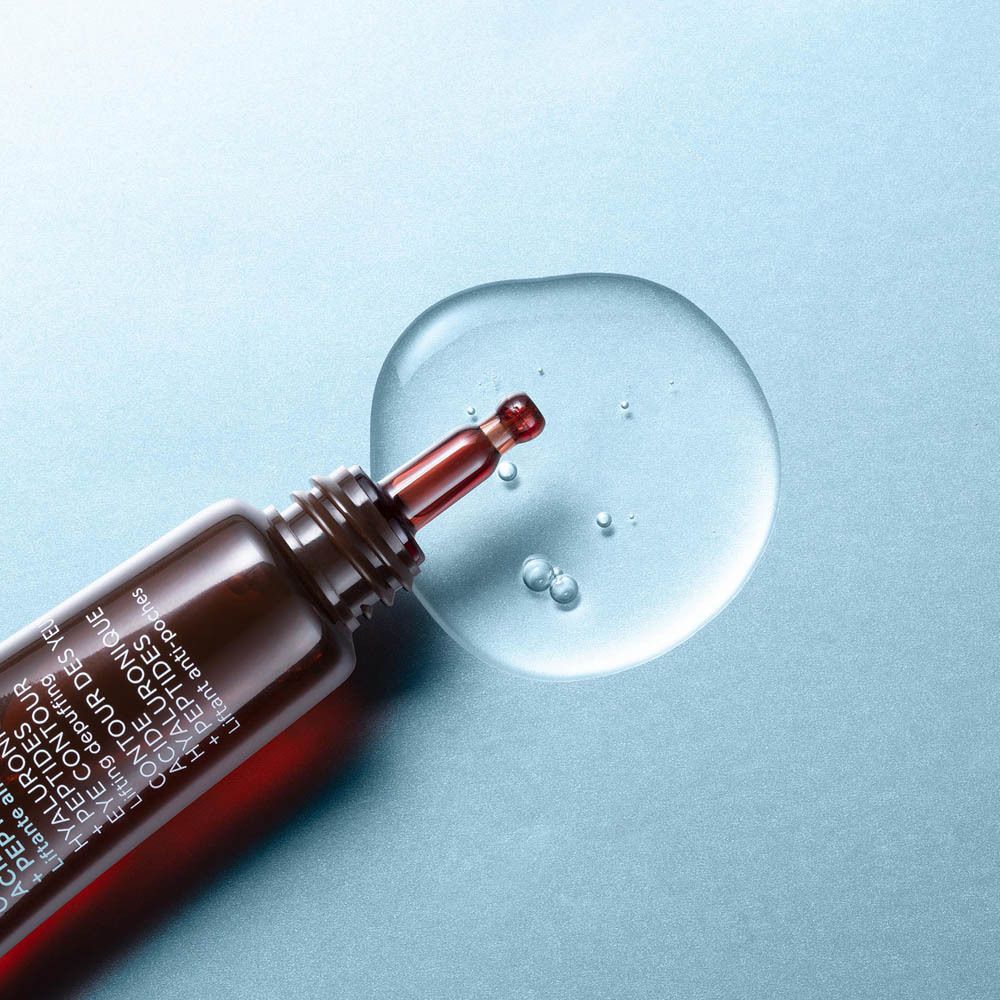 Tropfen transparente Flüssigkeit. Brauner Applikator. Hintergrund hellblau.