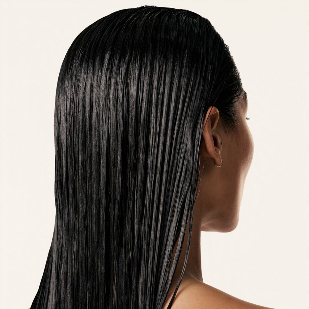 Rückansicht einer Person mit glänzendem, schwarzem Haar. Haare nass und glatt.