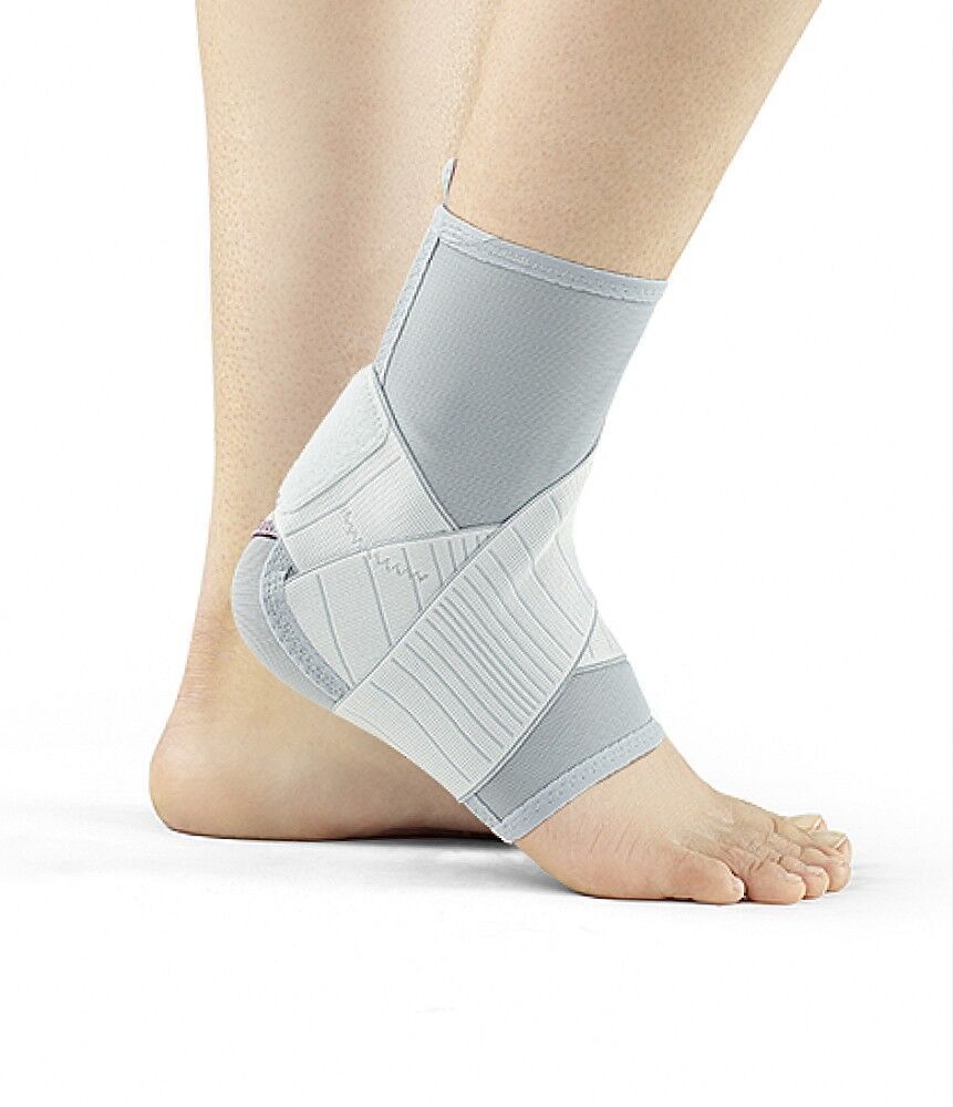 Knöchelbandage, grau-weiß. Bandage am Fuß getragen. Klettverschlüsse und Verstärkungen sichtbar.