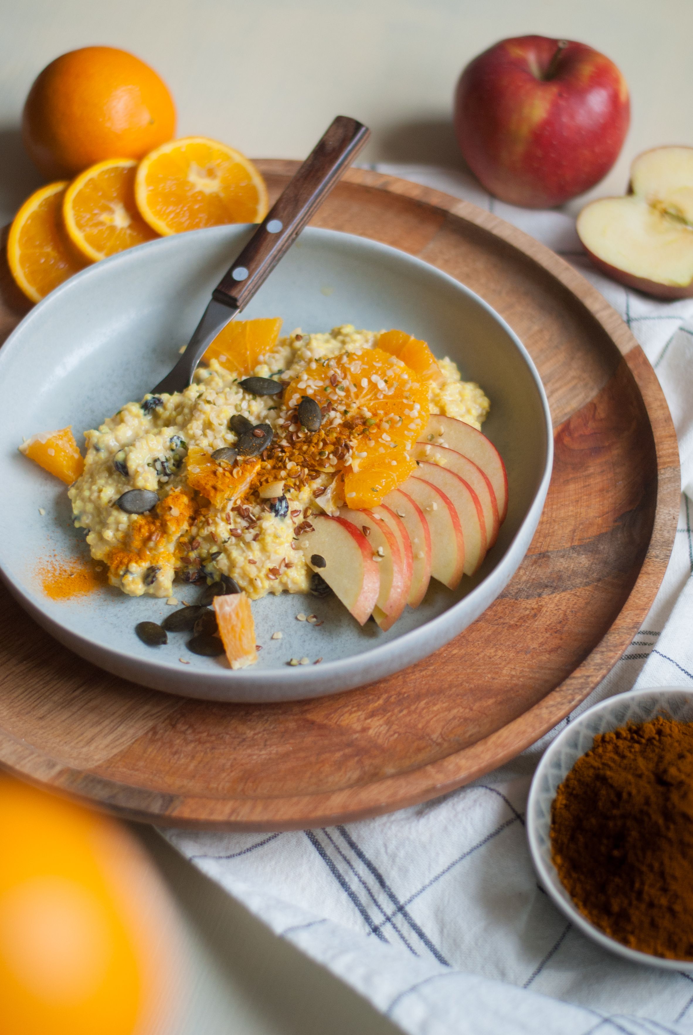 Schüssel mit Haferbrei garniert mit Orangen, Äpfeln und Kürbiskernen, bestreut mit Zimt.
