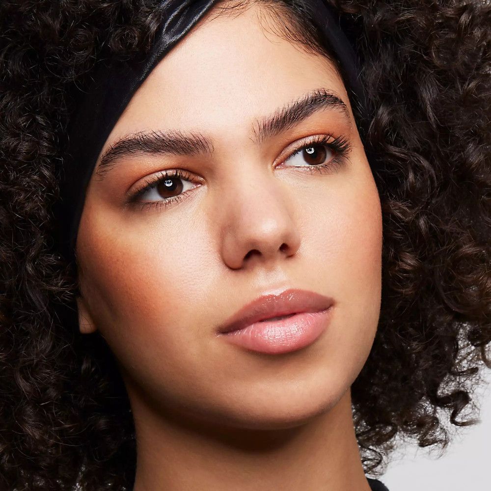 Nahaufnahme eines Gesichts mit Make-up. Augenbrauen, Lider und Lippen geschminkt. Schwarzes Stirnband. Hautton: hell.