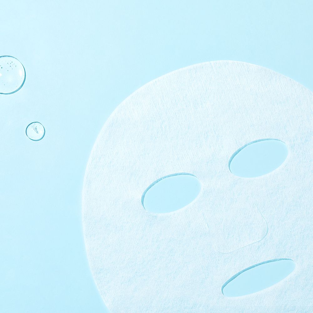 Weiße Gesichtsmaske mit Aussparungen für Augen, Nase und Mund. Auf blauem Hintergrund, mit Wassertropfen.