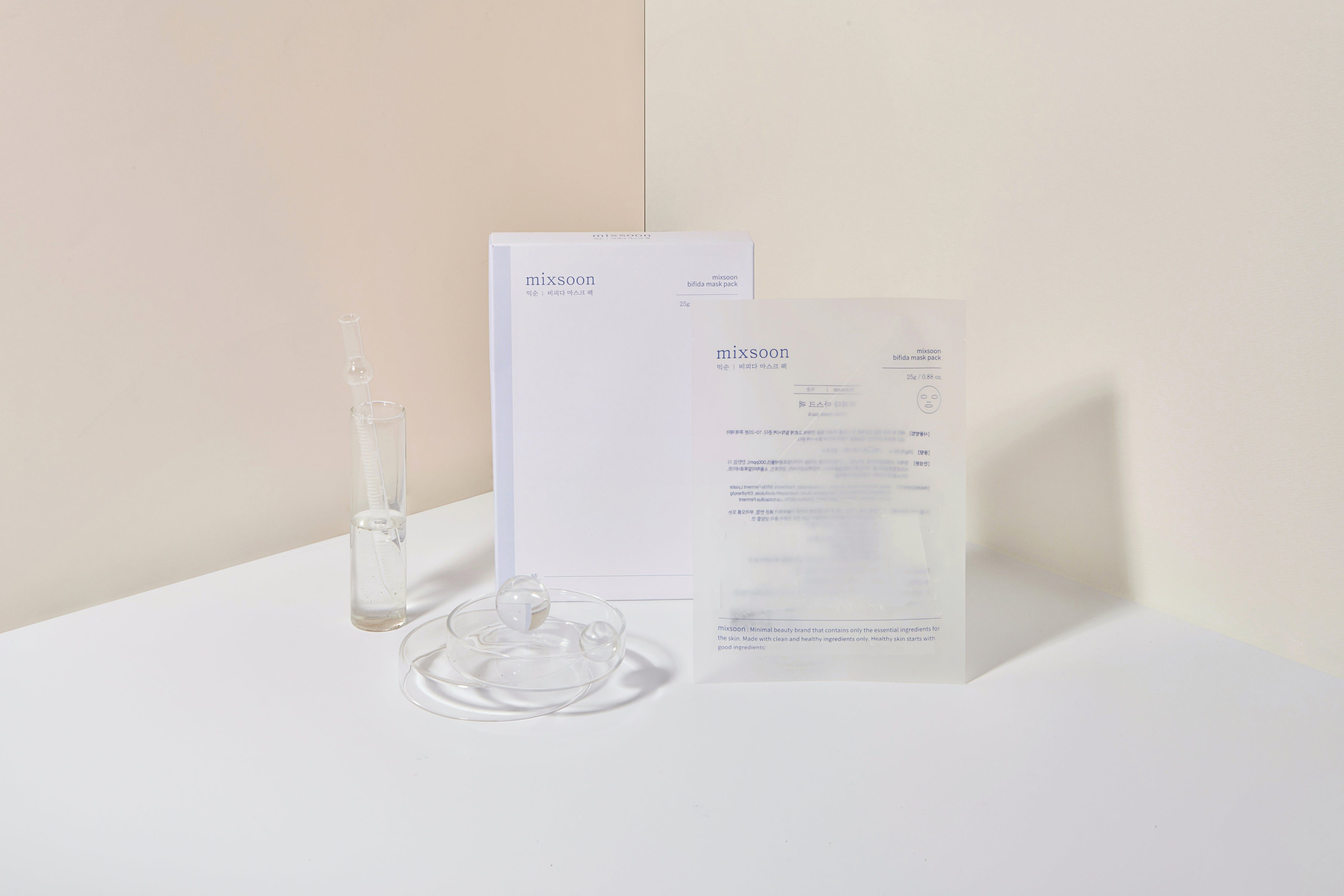 Verpackung und Zubehör. Ein Glasbehälter mit Flüssigkeit, ein Becher, eine Maskenpackung und ein Papierstapel.