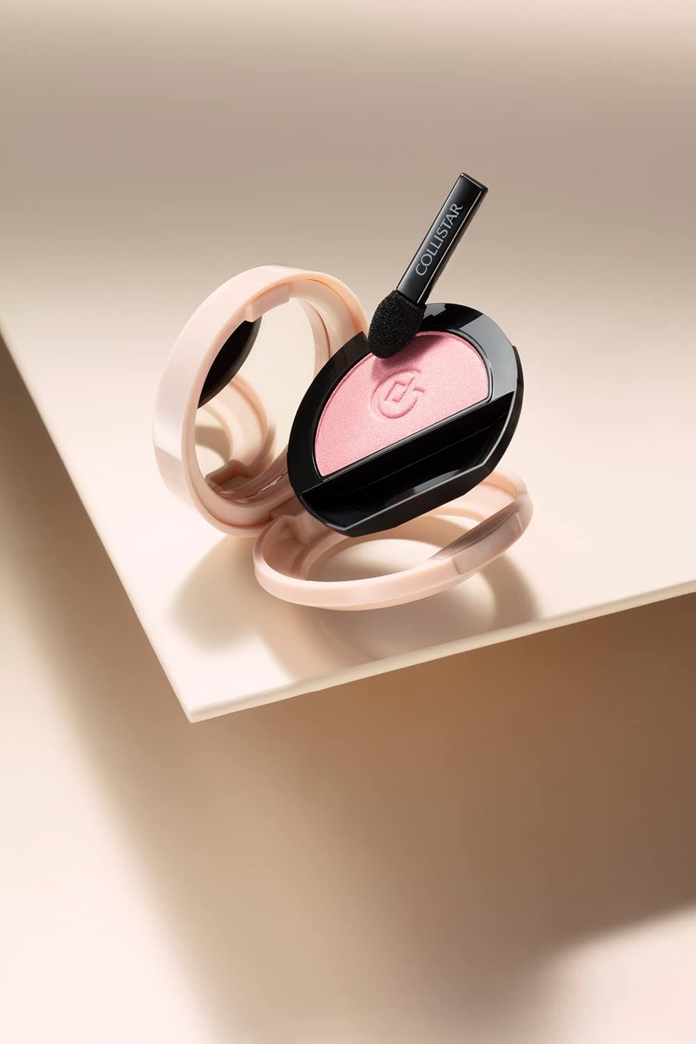 Ombretto Compatto Impeccabile in rosa, mit Spiegel und Applikator. Auf einer Oberfläche platziert.