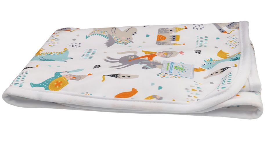 Wickelunterlage mit Ritter- und Drachenmuster. Weiß mit farbigen Motiven. Aufgerollt, mit weißem Rand und Etikett.