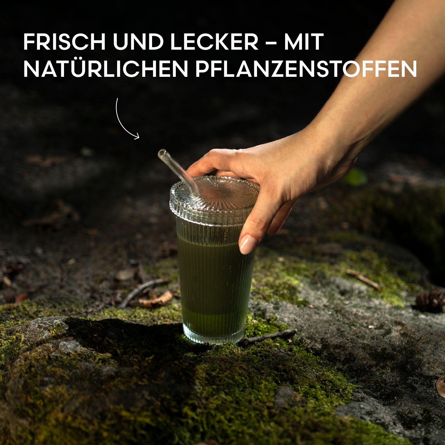 Glas mit grünem Getränk und Strohhalm. Hand hält Glas. Aufschrift: Frisch und lecker - mit natürlichen Pflanzenstoffen.