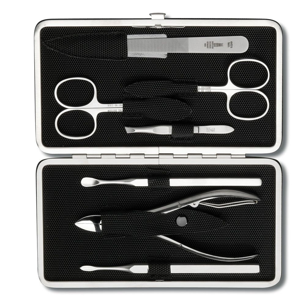 Offener Maniküre-Etui mit silbernen Werkzeugen auf schwarzem Stoff. Enthält Schere, Feile, Nagelknipser und weitere Instrumente.