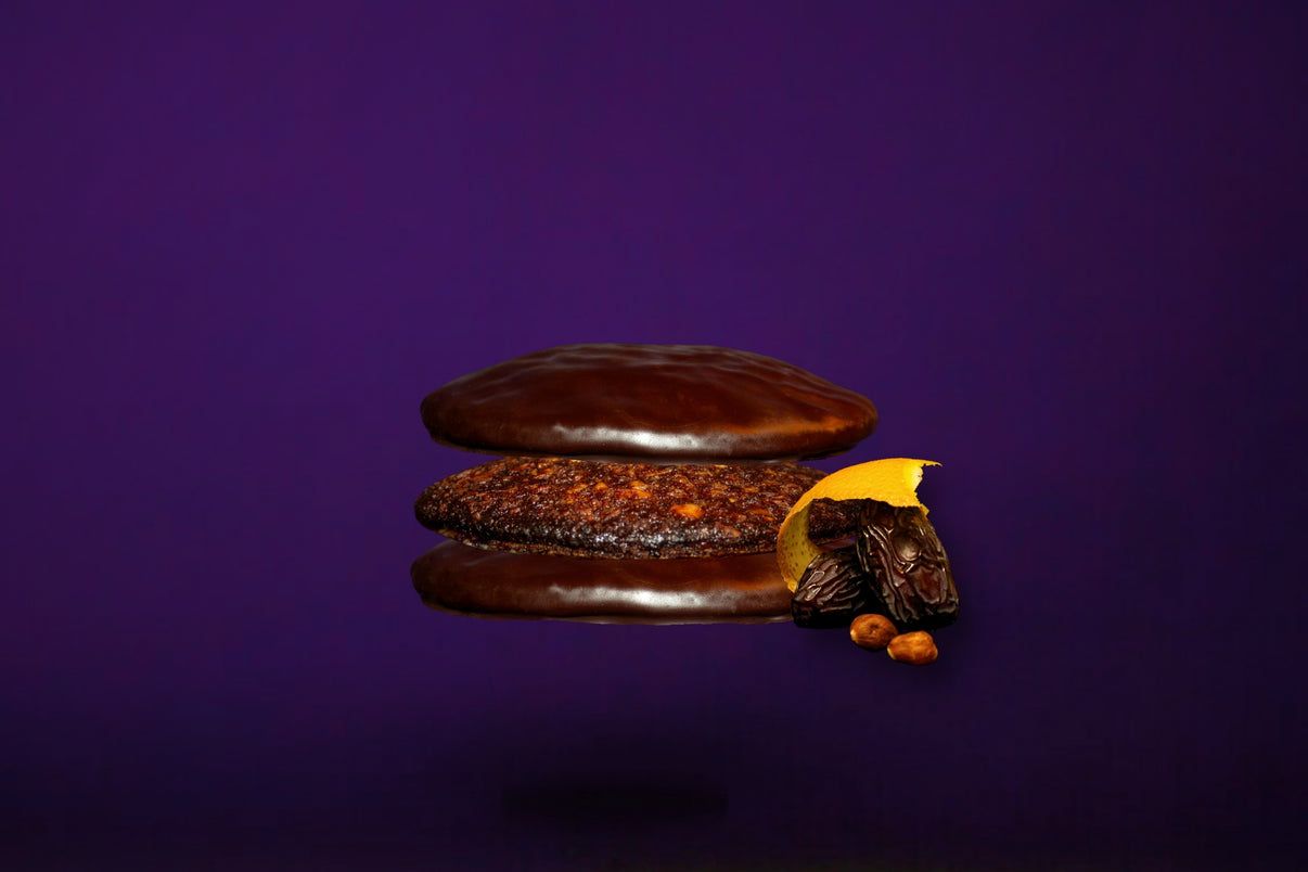 Drei Odilia Bio Elisen Lebkuchen mit Schokoladenüberzug, garniert mit Nüssen und Orange.