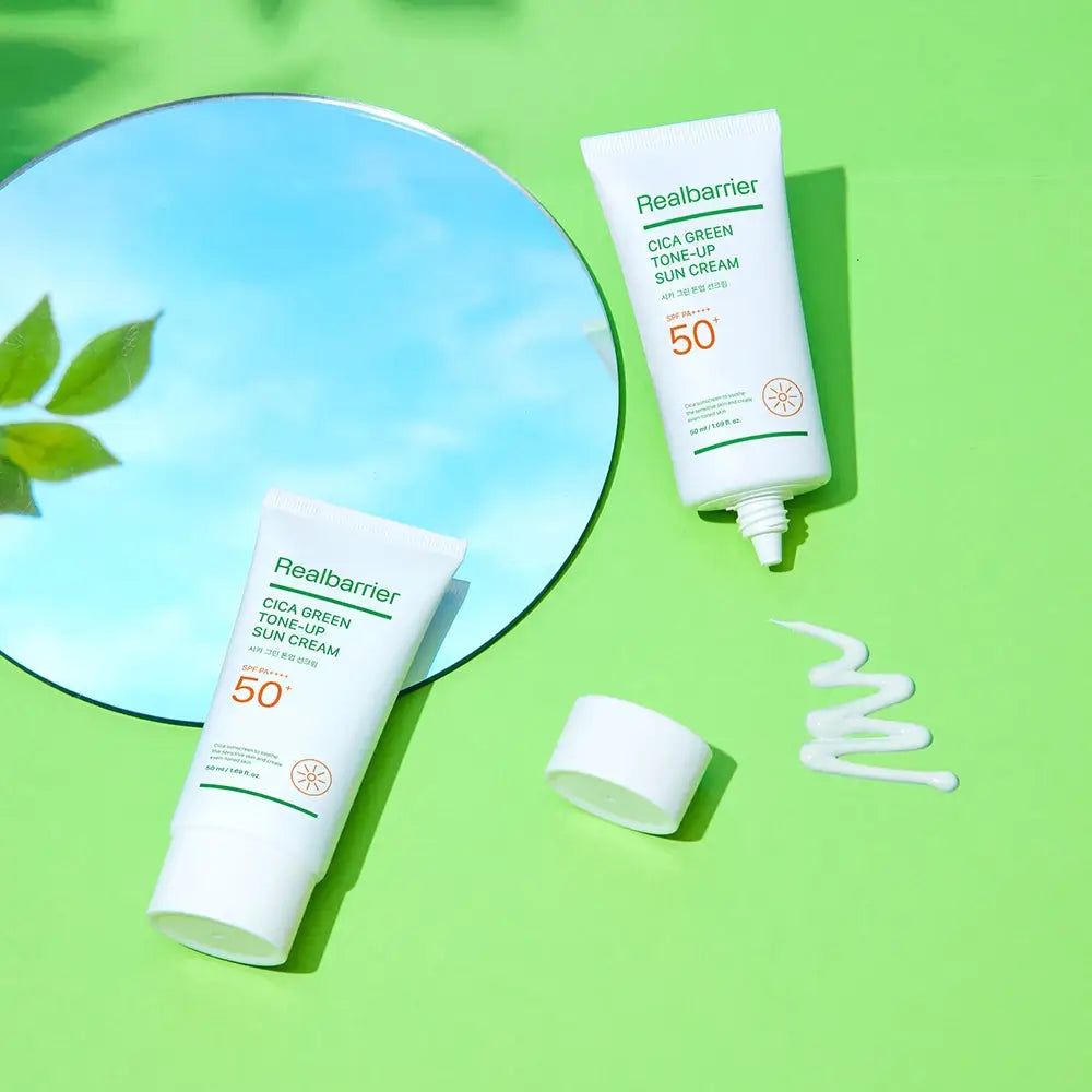 Zwei Tuben Real Barrier Sonnencreme, eine mit geöffnetem Deckel, daneben ein Klecks Creme. Spiegel im Hintergrund.
