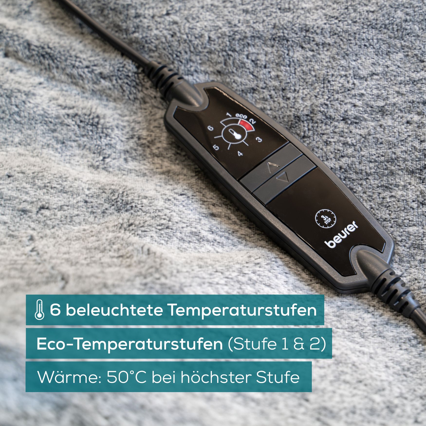 Nahaufnahme des Handbedienteils einer grauen Wärmezudecke. 6 beleuchtete Temperaturstufen. Marke Beurer.