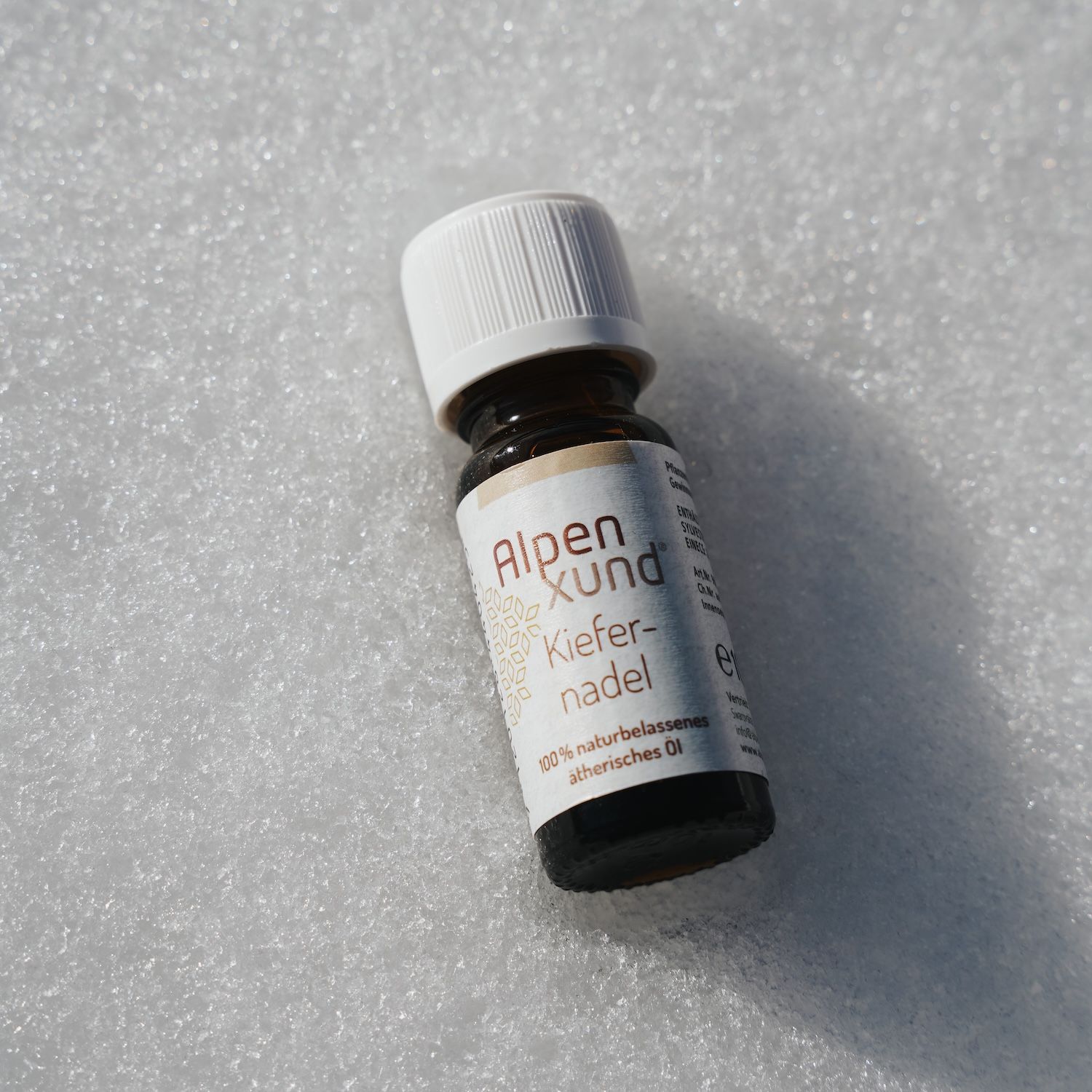 Braune Glasflasche mit weißem Deckel. Etikett mit "AlpenXund Kiefernnadel". Auf weißem Untergrund.