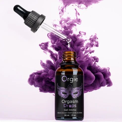 Braune Flasche mit schwarzem Etikett. Text: Orgie, Orgasm Drops, Gel intimo, clitoral arousal. Pipette. Lila Rauch im Hintergrund.