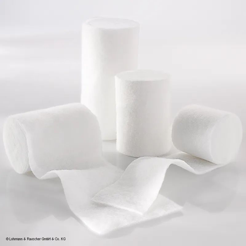 Mehrere weiße, zylindrische Bandagen, teilweise abgerollt. Aufschrift: Lohmann & Rauscher GmbH & Co. KG.