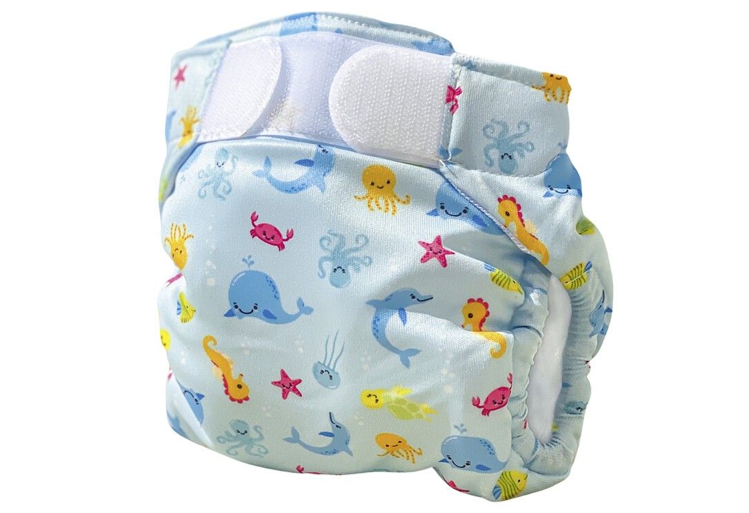 Schwimmwindel mit Meeresmotiven. Hellblauer Stoff mit Klettverschlüssen. Motive: Wale, Fische, Oktopusse, Seepferdchen.