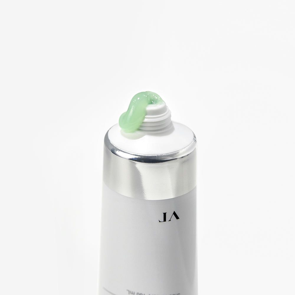 Nahaufnahme einer Tube. Weiße Tube mit silbernem Deckel, grüne Creme tritt aus der Öffnung aus.