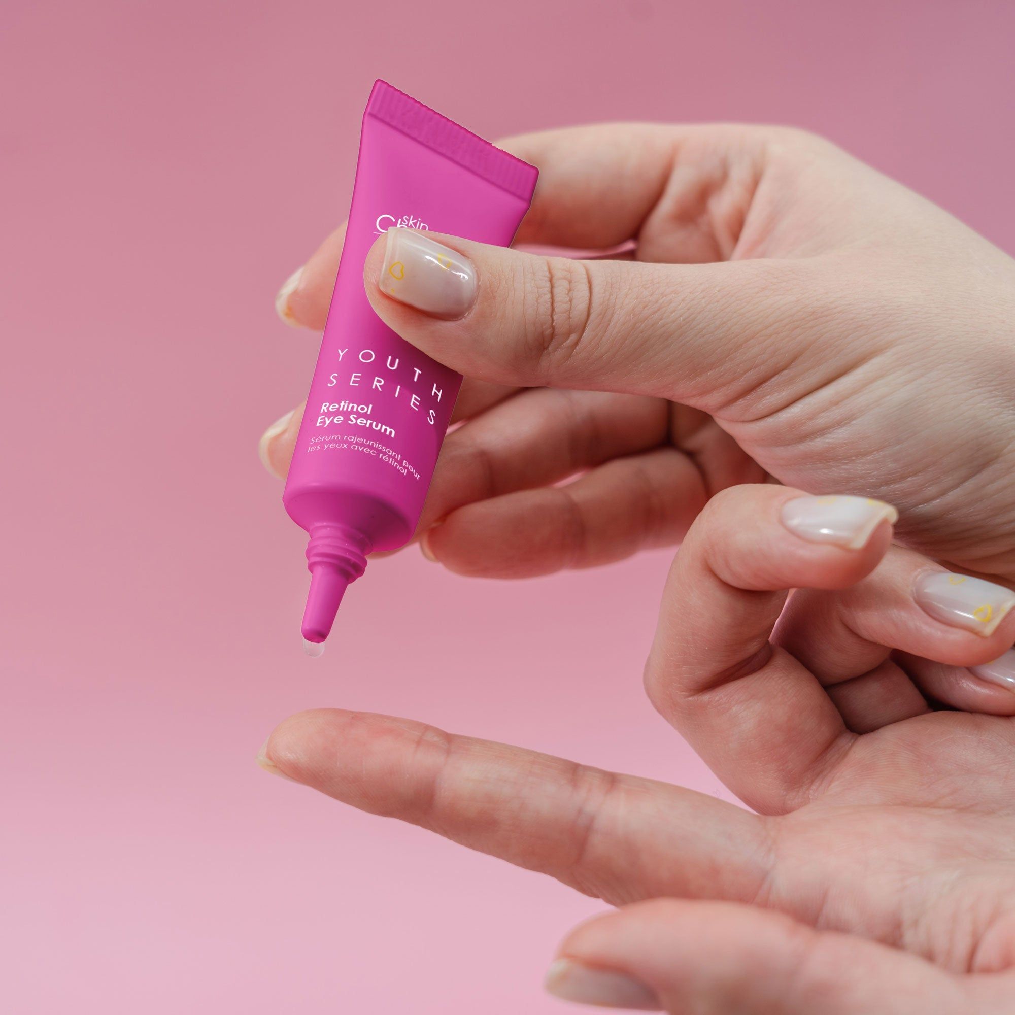 Rosa Tube wird von einer Hand gehalten. Auf rosa Hintergrund.