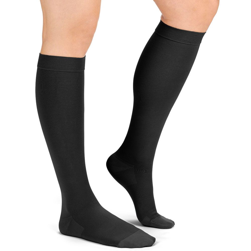 Beine mit schwarzen Kompressions-Kniestrümpfen. Die Strümpfe bedecken den Fuss bis zum Knie.