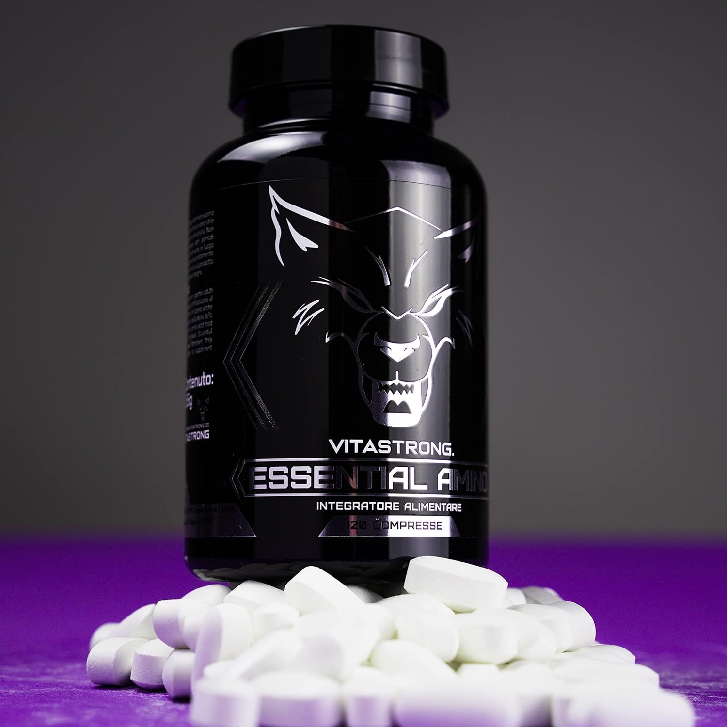 Schwarze Flasche Vitastrong Essential Amino, Tabletten darunter. Aufschrift und Wolf Logo. Lila Hintergrund.