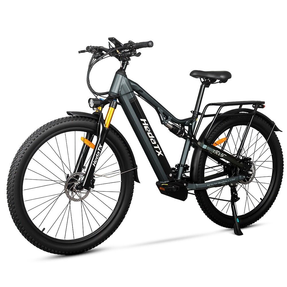 Graues E-Bike HedaTX TX19. Schwarze Reifen, Gepäckträger, Federung. Gelbe Gabel. 27 Gänge. Aufschrift HedaTX.