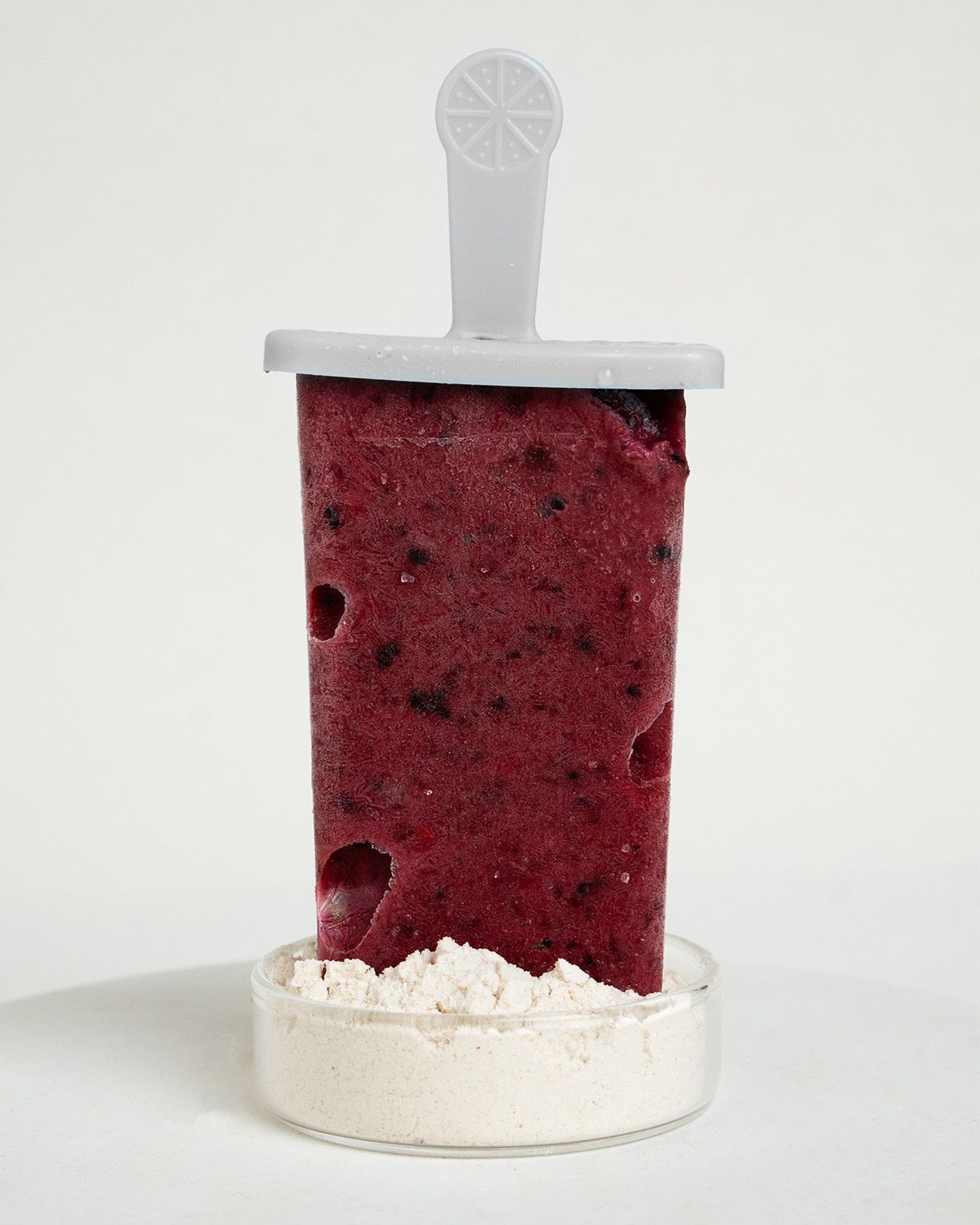 Eis am Stiel mit Beeren, umgeben von Johannisbrotkernmehl.