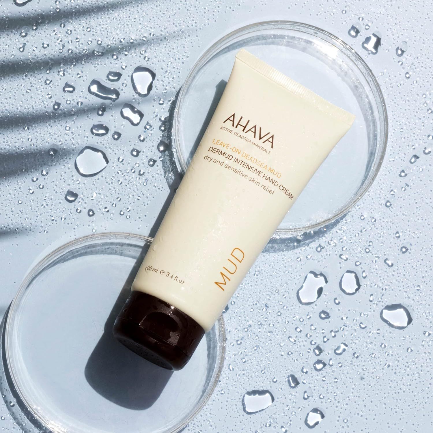 AHAVA Dermud Intensive Hand Cream Tube auf Glasplatten. Wasser und Schatteneffekte. Brauner Verschluss.