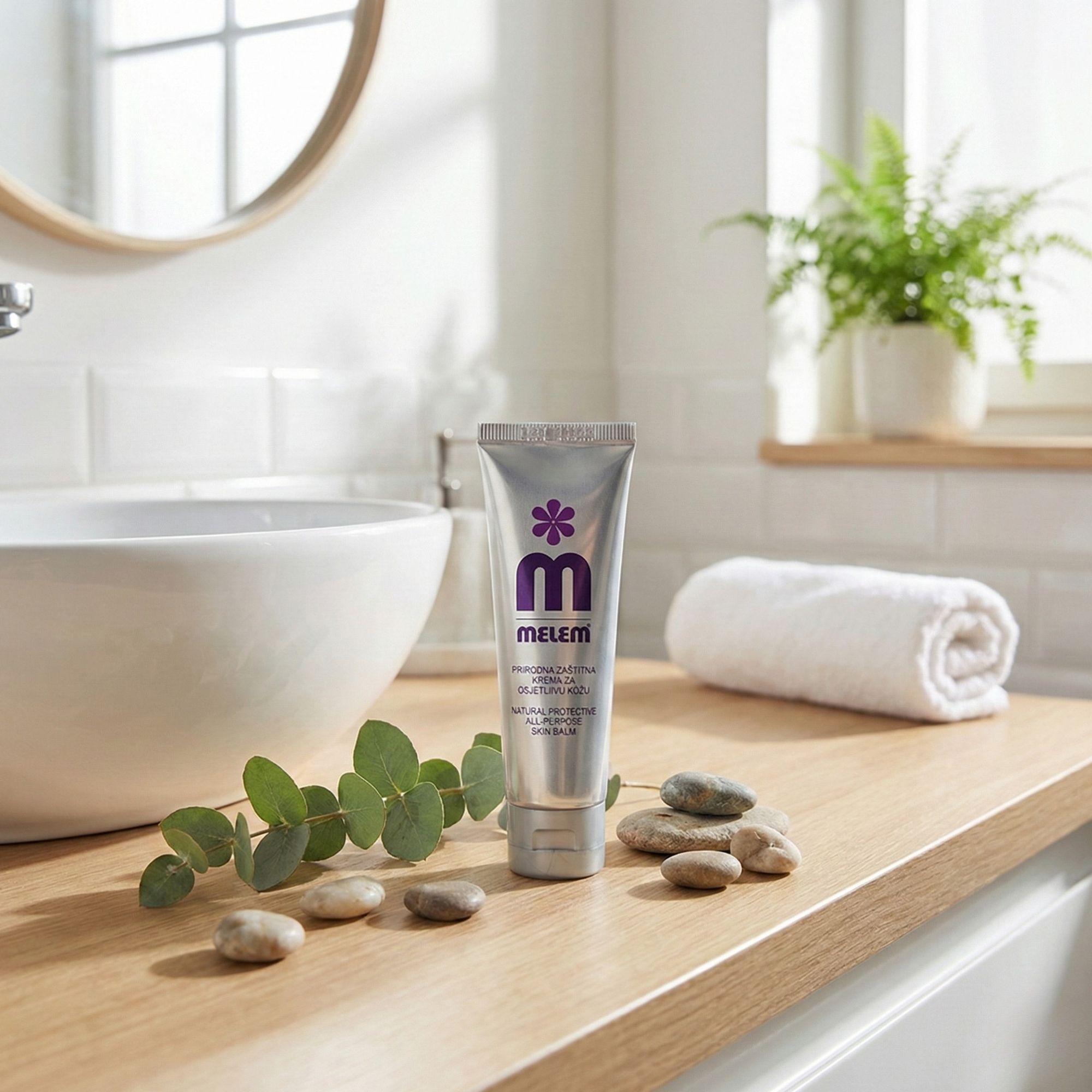 Silberne Tube mit lila Logo und Schriftzug MELEM auf einer Holzoberfläche. Dekoration: Steine, Zweig, Handtuch.