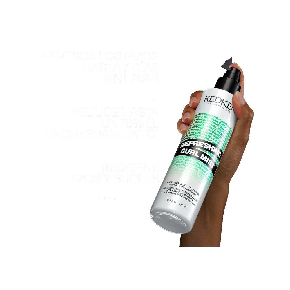 Person hält Redken Refreshing Curl Mist. Weiße Flasche mit schwarzem Sprühkopf. Text: Refreshing Curl Mist, Redken, 5th Avenue NYC.
