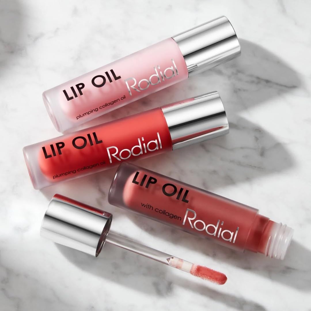 Drei Lippenöl-Flakons. Aufschrift: LIP OIL, Rodial. Farben: Rosa, Koralle, Rotbraun. Silberne Kappen und Applikatoren.