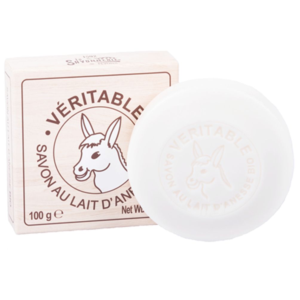 Runde, weiße Seife und Karton. Aufschrift: VERITABLE SAVON AU LAIT D'ÂNESSE. Logo: Eselkopf. 100 g.
