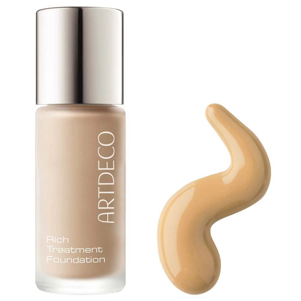 Artdeco Rich Treatment Foundation Flasche und Klecks. Beige Flüssigkeit, silberner Deckel. Produktname sichtbar.