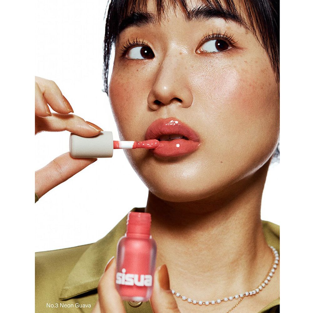 Frau hält eine Flasche Lippen-Plumper und trägt ihn auf. Aufschrift: sisu. Produktname: No.3 Neon Guava.