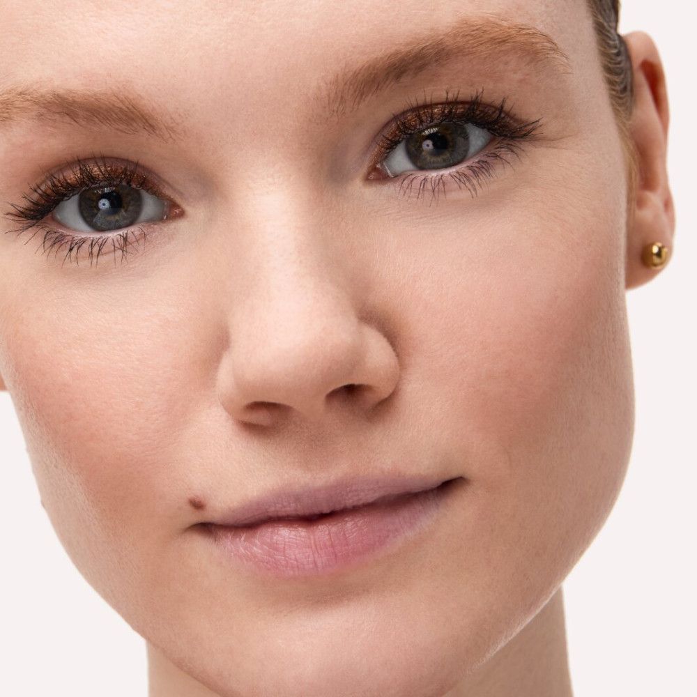 Nahaufnahme eines Gesichts. Hautton, Augenbrauen, Wimpern und Augen. Goldener Ohrstecker.