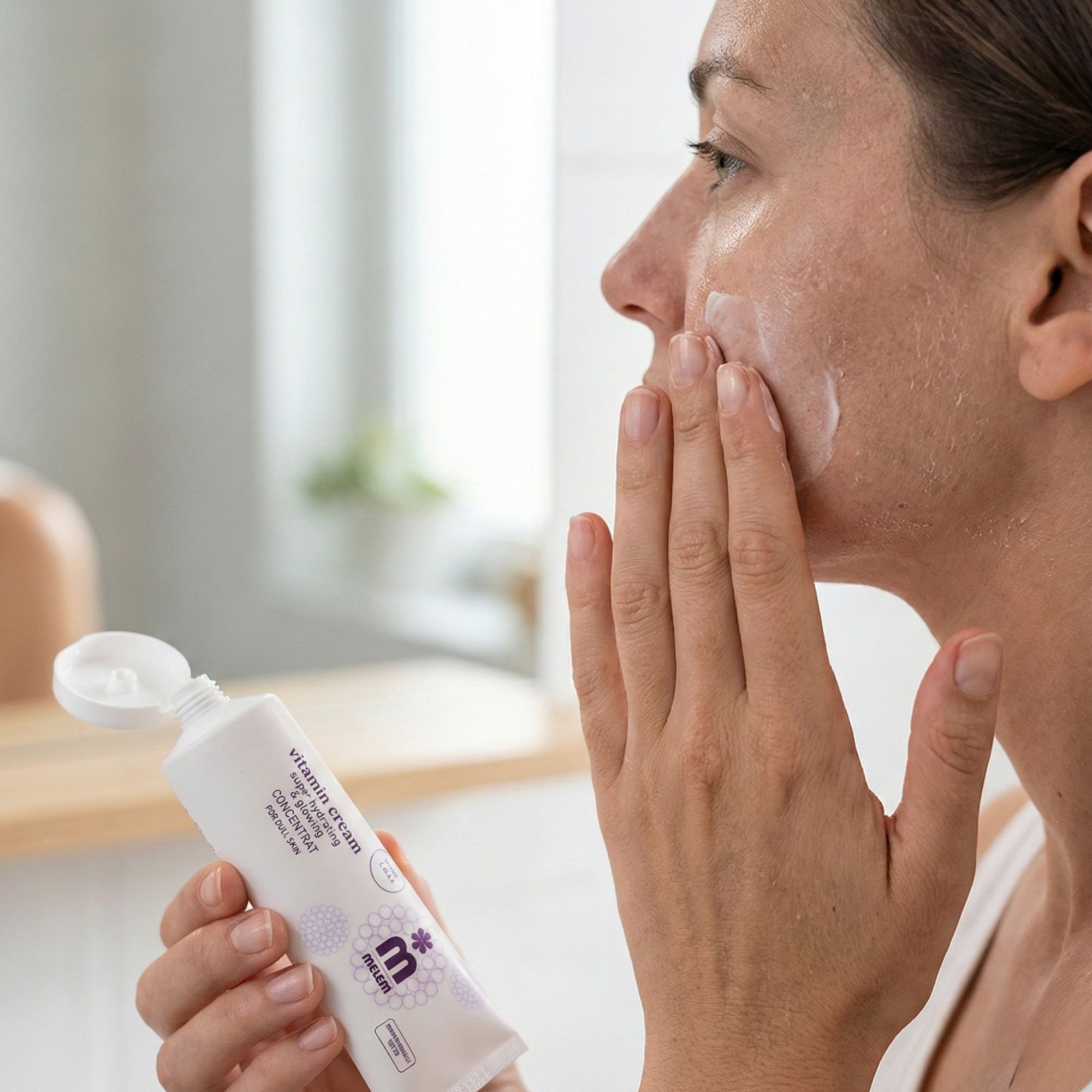 Frau trägt Creme auf. Tube mit Produktnamen und Logo sichtbar. Text: Vitamin Cream, super hydrating & glowing, CONCENTRAT.