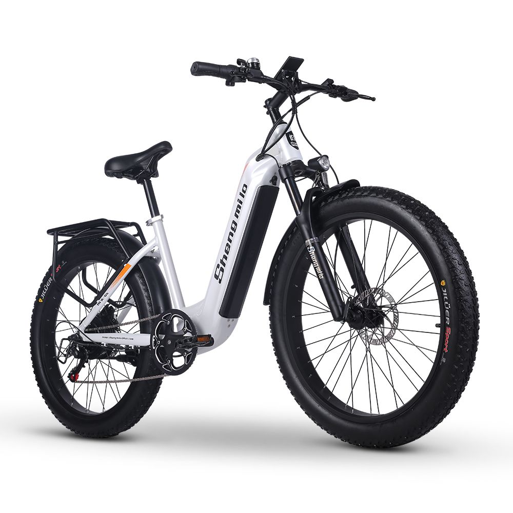 Weißes E-Bike mit schwarzen Reifen und Gepäckträger. Orangefarbene Akzente. Marke Shengmilo.