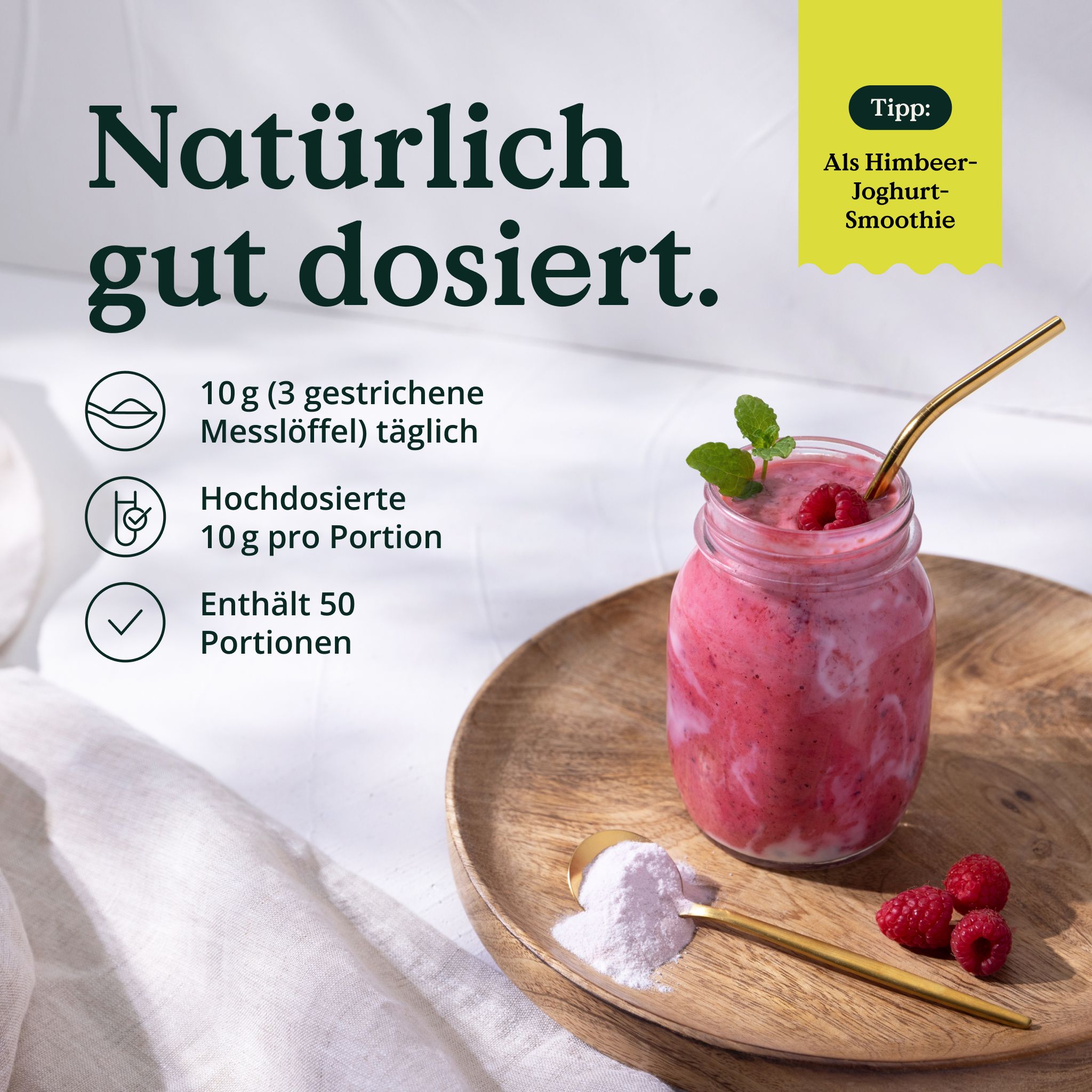 Glas mit Himbeer-Joghurt-Smoothie, daneben Löffel mit Pulver. Aufschrift: 10g pro Portion, enthält 50 Portionen. Auf Holztablett.