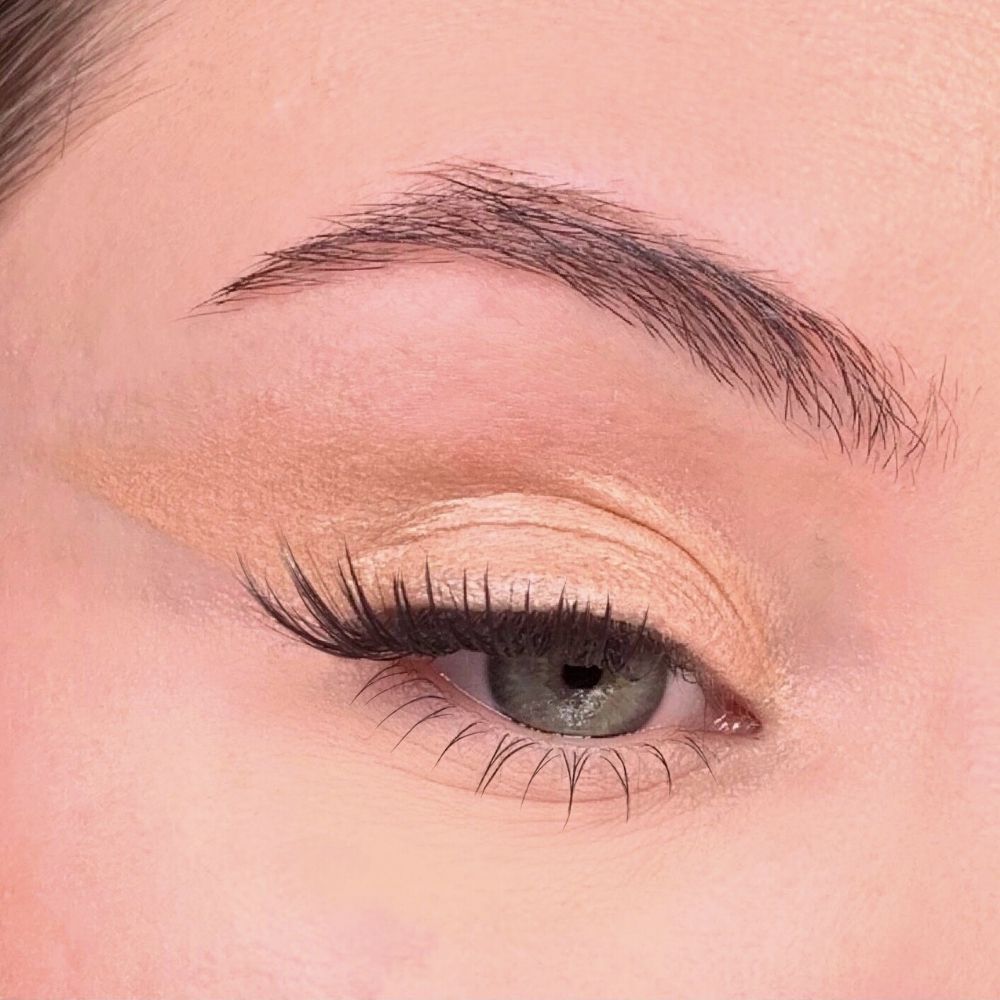 Auge mit Lidschatten. Beige Lidschatten auf dem Augenlid. Wimpern und Augenbraue sichtbar.