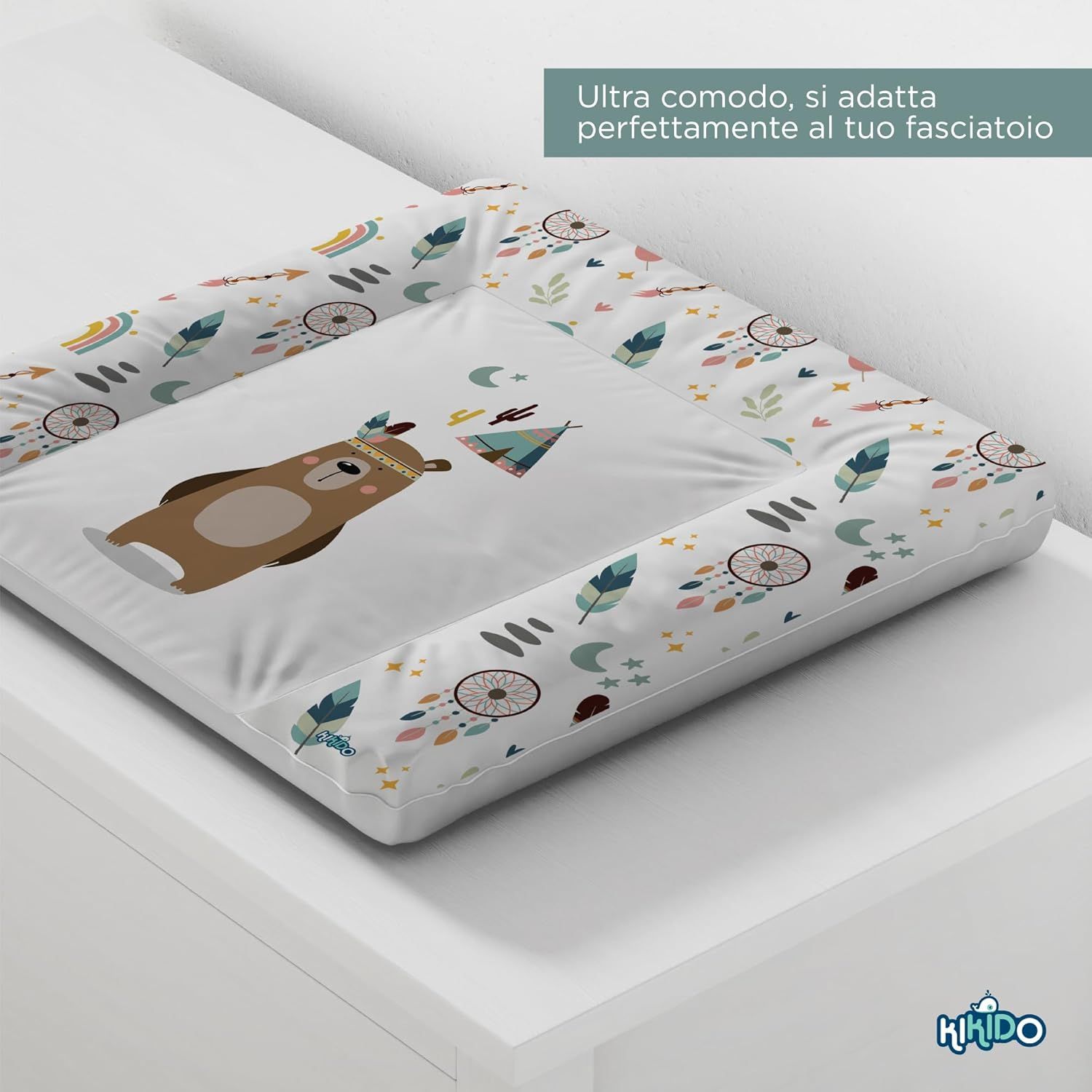 Wickelauflage mit Bären-Motiv. Weißer Hintergrund mit Federn, Traumfängern und einem Zelt. Kikido-Logo.