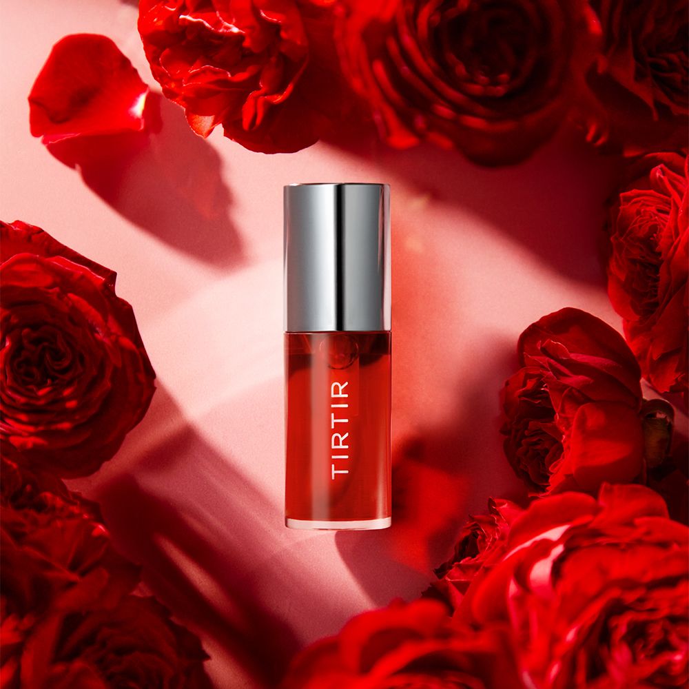 Rotes Lip Oil mit silbernem Deckel, umgeben von roten Rosen. Produktname: TIR TIR.