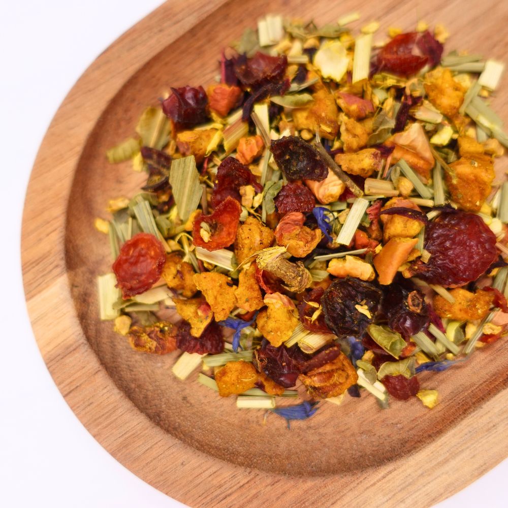 Tee-Mischung auf Holzschale. Sichtbar sind getrocknete Früchte, Kräuter und Blüten. Helle und dunkle Farbtöne.