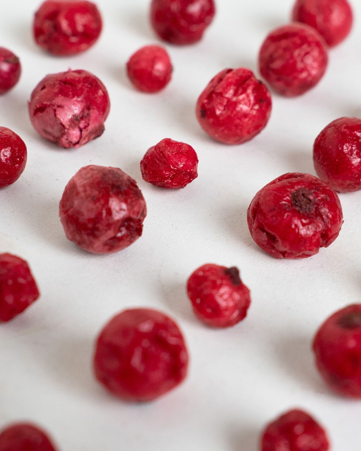 Nahaufnahme von gefriergetrockneten roten Johannisbeeren auf weißem Hintergrund.