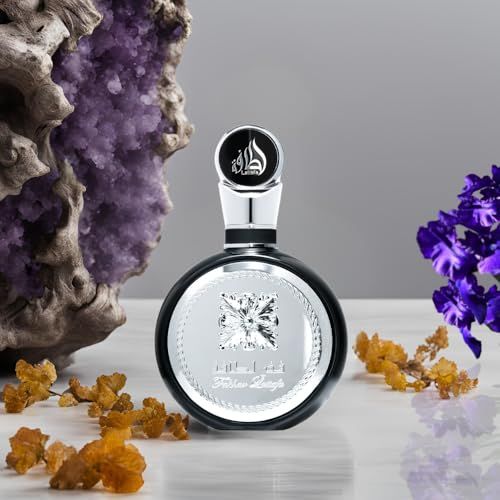 Runde, schwarze Parfumflasche mit silberner Verzierung. Umgeben von Dekoration.