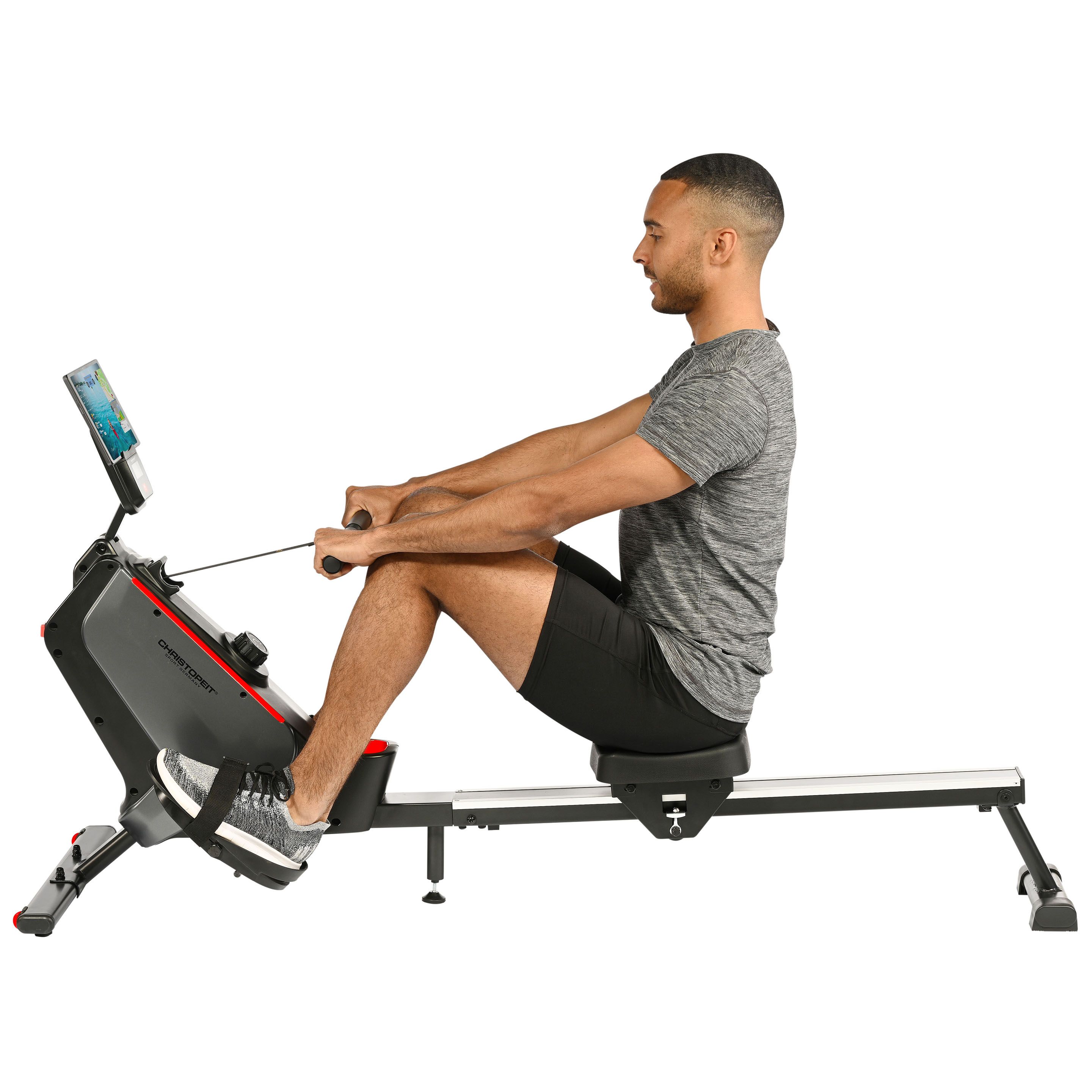 Rudergerät mit Person. Schwarzes Gerät mit roter Akzentfarbe. Person sitzt auf dem Sitz und zieht am Griff.