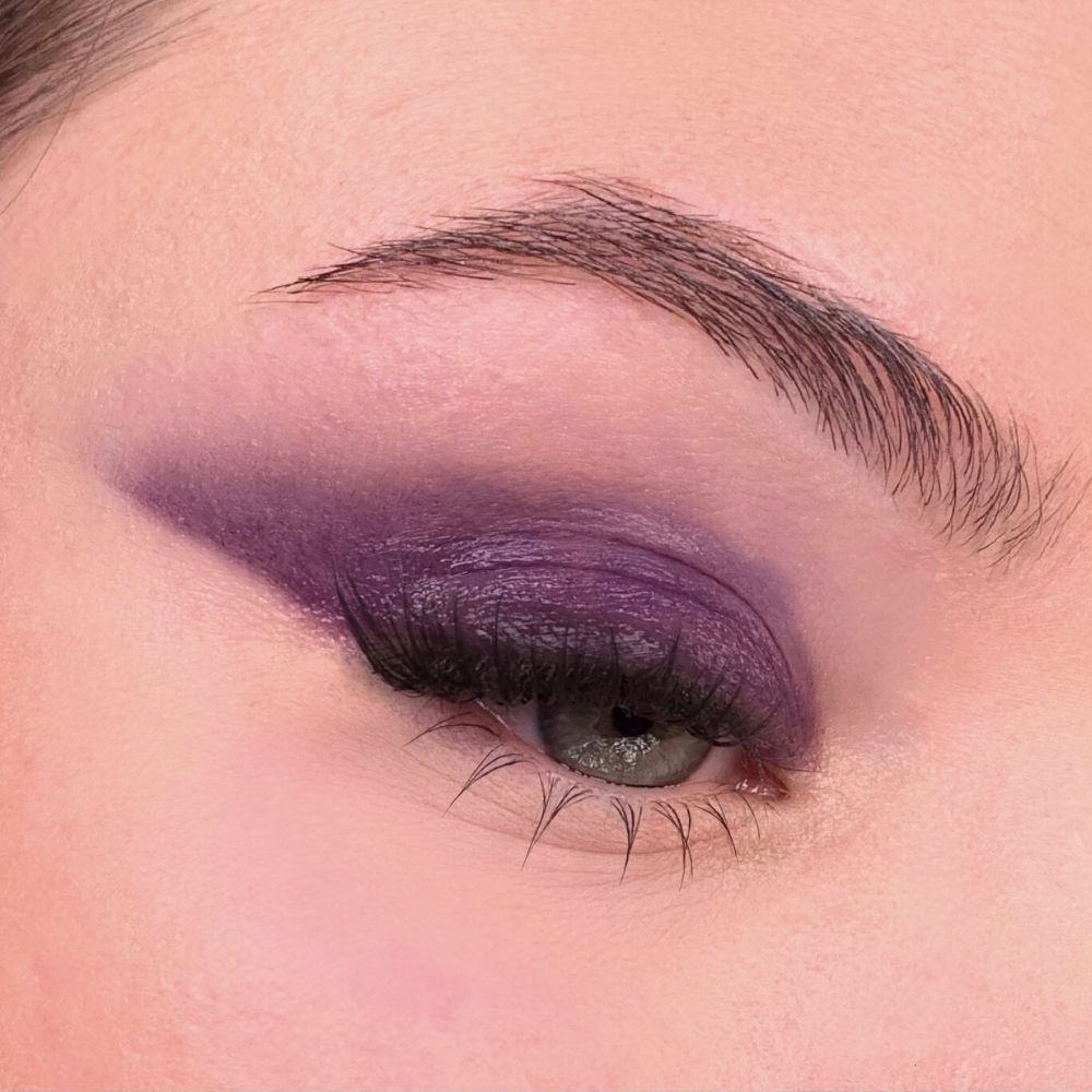Auge mit violettem Lidschatten. Augenlid mit dunklem, violettem Lidschatten. Braue und Wimpern sichtbar.