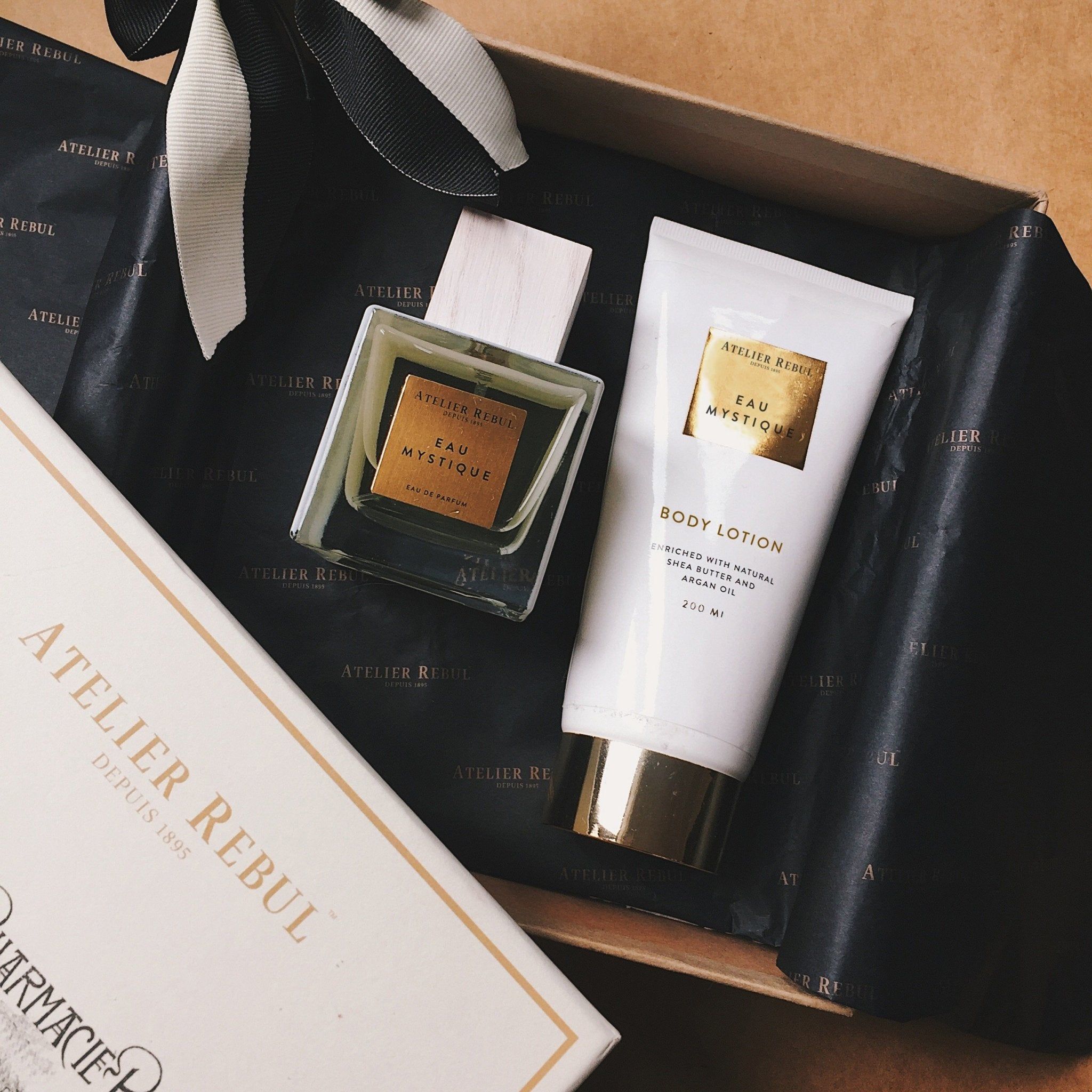 Eau Mystique Eau de Parfum und Bodylotion. Weiße Tube und quadratischer Flakon. Schwarze Geschenkbox mit Schleife.