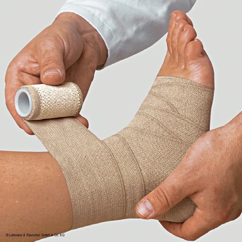 Verband wird um einen Fuß gewickelt. Beige elastische Bandage. Hände halten und wickeln das Band.